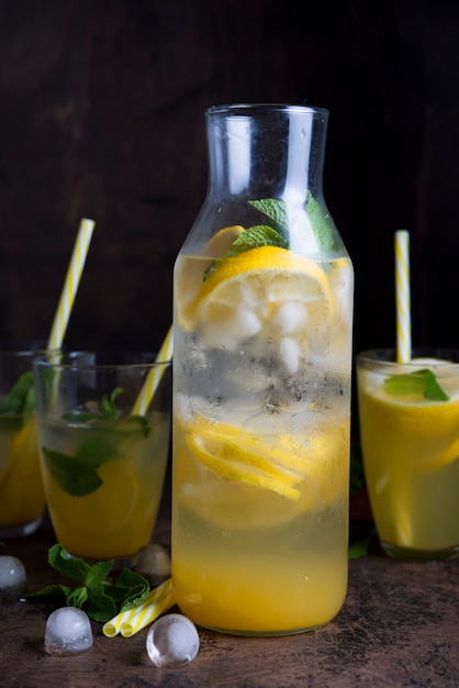 Homemade orange lemonade with citrus and mint on a dark wooden space