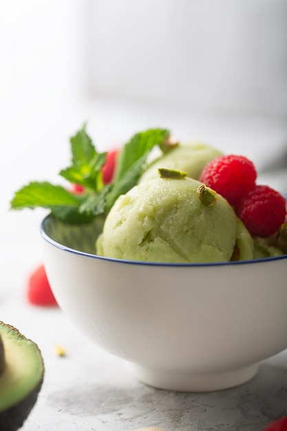 Homemade organic avocado and mint ice cream in a bowl with raspberries