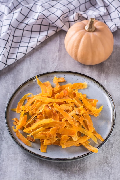 Homemade organic baked pumpkin chips on a plate on the table vertical view