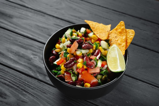 Homemade organic cowboy caviar dip with corn beans and chips on dark wooden background