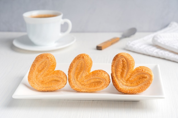 Homemade palmier cookies with sugar baked dessert served on rectangular plate with cup of coffee