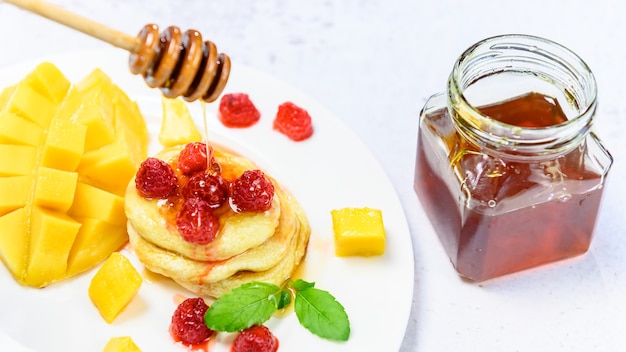 Homemade pancake with honey and raspberry. Dessert with sweet mango.