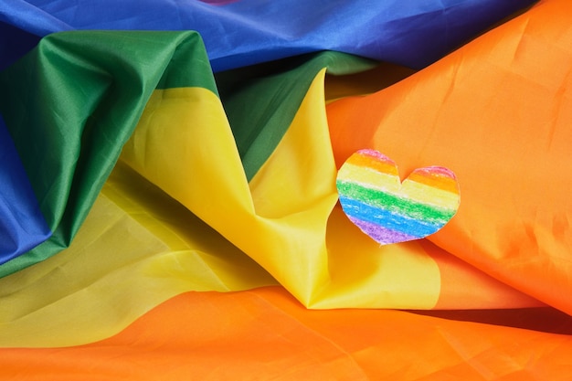 Homemade paper heart in the colors of the lgbt community pride flag on a large fabric flag