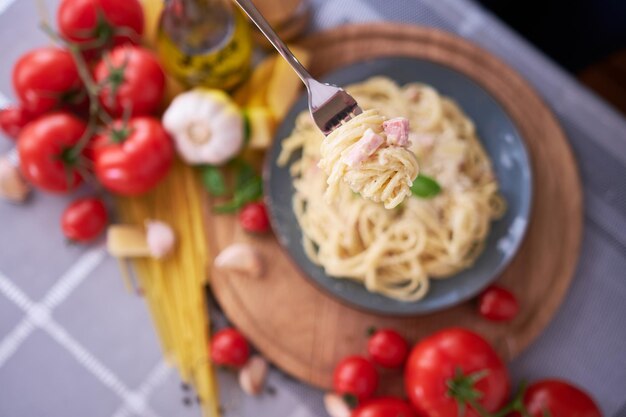 Homemade pasta carbonara with fresh basil and parmesan in ceramic dish