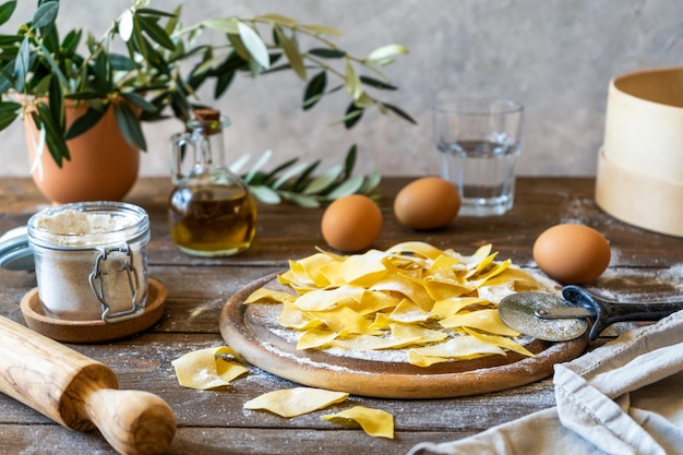 Homemade pasta Maltagliati on cutting board with ingredients