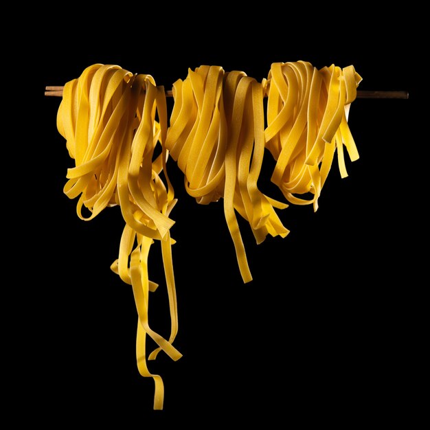 Homemade pasta rolled on a wooden stick on a dark background