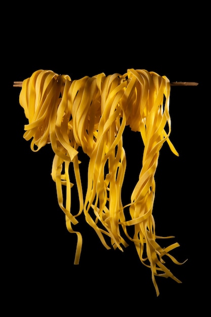 Homemade pasta rolled on a wooden stick on a dark background