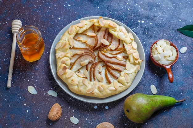 Homemade pear galette pie with almond leaves and fresh ripe green pears