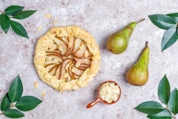 Homemade pear galette pie with almond leaves and fresh ripe green pears