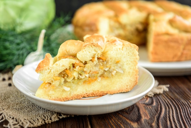 Homemade pie with cabbage, carrot, onion and meat on wood