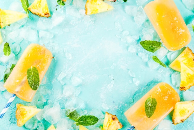 Homemade Pineapple Popsicles on Ice with fresh Pineapple slices and mint