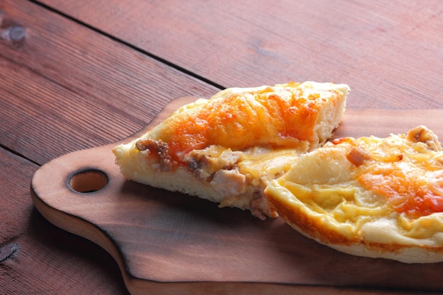 Homemade pizza on cutting board Sliced pizza on wooden background in rustic style Italian cuisine