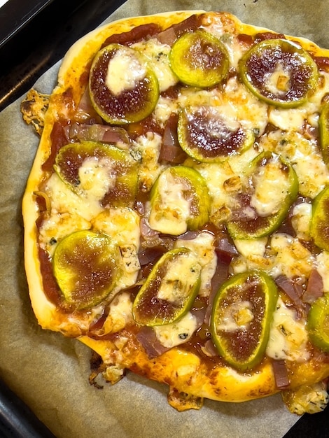 Homemade pizza with figs and bacon lies on a baking sheet