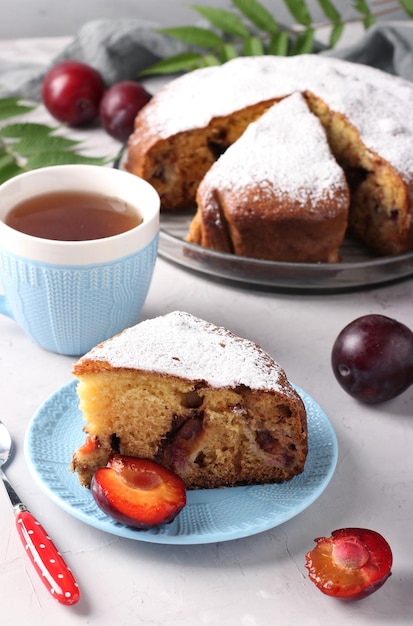 Homemade plum pie with a cut piece on a plate on a light background closeup Vertical format