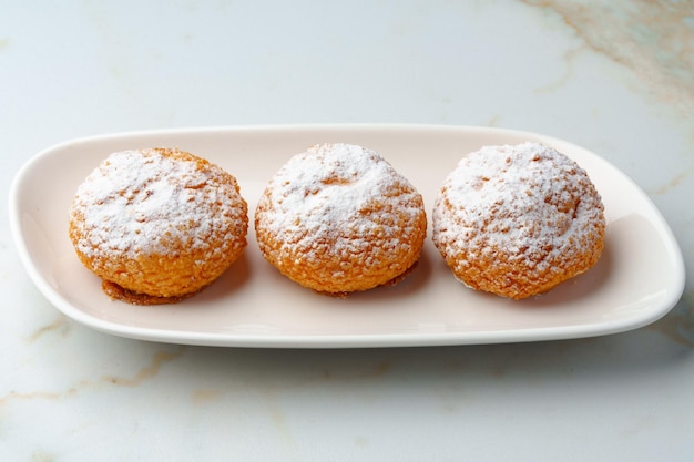 Homemade profiteroles with powdered sugar on white plate