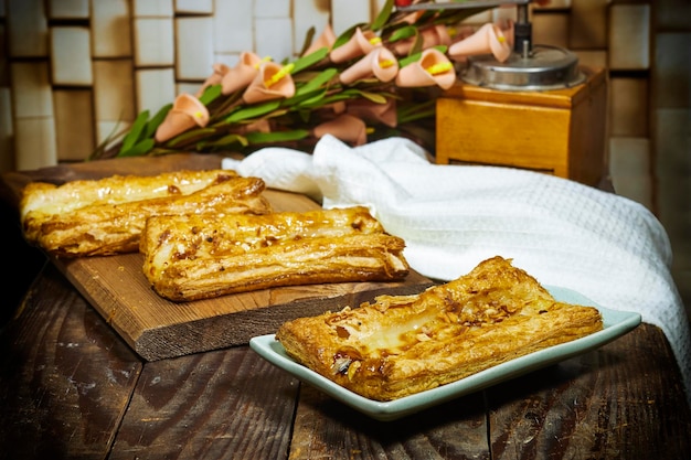 Homemade puffed pastry apple tart with calla lilies and coffee grinder on wood table