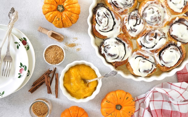 Homemade pumpkin cinnamon rolls with cream cheese in a baking dish flat lay top veiw seasonal autumn