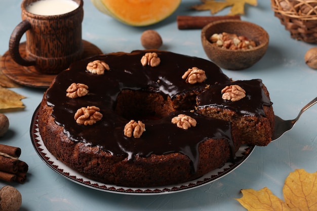 Homemade pumpkin muffin decorated with chocolate icing and walnuts on a light blue background, Closeup, horizontal orientation