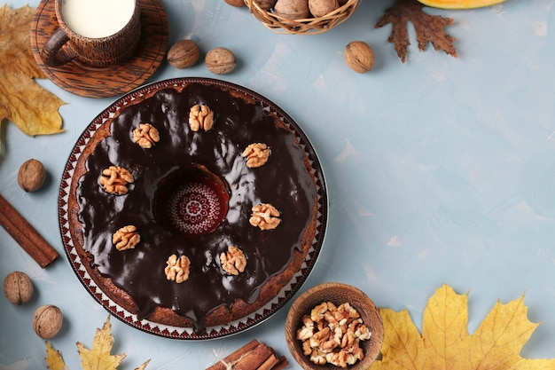 Homemade pumpkin muffin decorated with chocolate icing and walnuts on a light blue