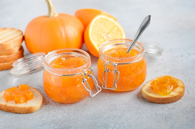 Homemade pumpkin and orange confiture in a jars on a gray concrete .