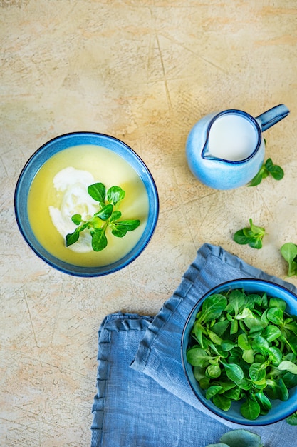 Homemade puree soup from fresh zucchini and yang spinach on light yellow background