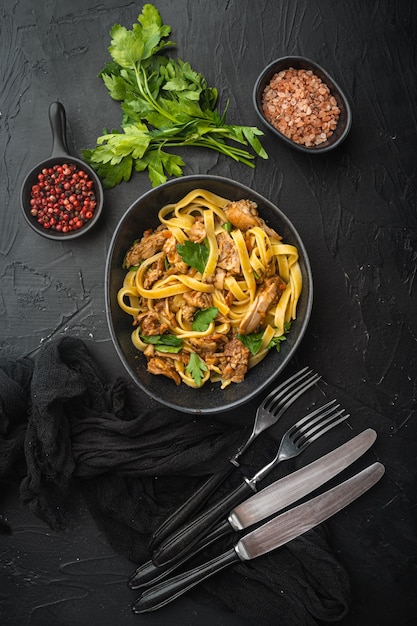 Homemade Rabbit stew pappardelle set, in bowl, on black stone table, top view flat lay