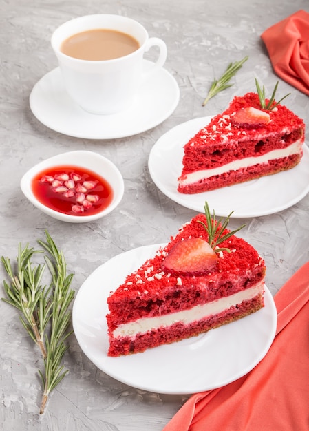 Homemade red velvet cake with milk cream and strawberry  with cup of coffee on a gray concrete surface with red textile