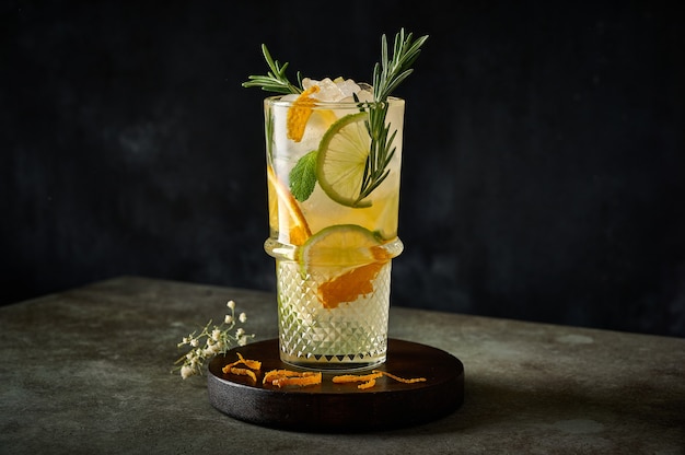 Homemade refreshing summer lemonade cocktail with orange juice crushed ice rosemary and citrus