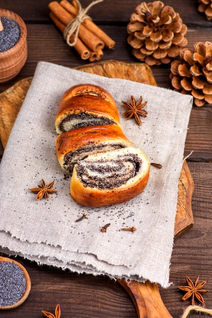 Homemade roll with poppy seeds on a brown wooden board