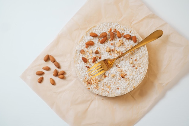 Homemade round cake with nuts on parchment paper Food delivery Homemade baking Top view Delicious tart with nuts and golden fork above on the white table