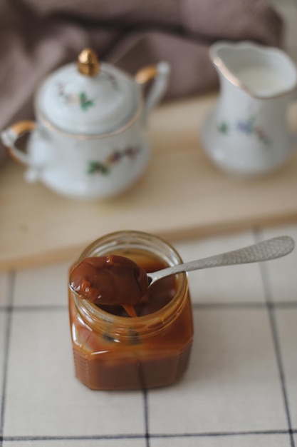 Homemade salted caramel sauce in jar on rustic wooden table