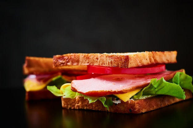 Homemade sandwich with lettuce and ham on a black background, close up