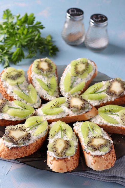 Homemade sandwiches with kiwi cream cheese and garlic on a plate on light blue background