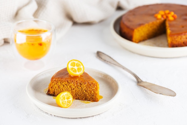 Homemade sea buckthorn cake with orange and kumquat on a plate with a glass of tea