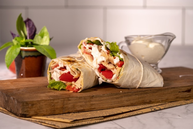 Homemade shawarma or burrito or chicken roll with vegetables and sauce