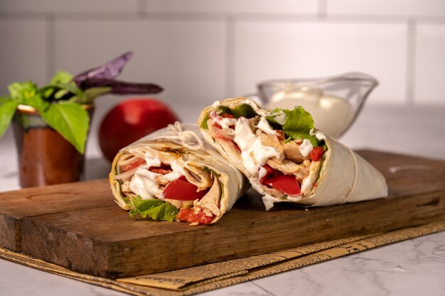 Homemade shawarma or burrito or chicken roll with vegetables and sauce