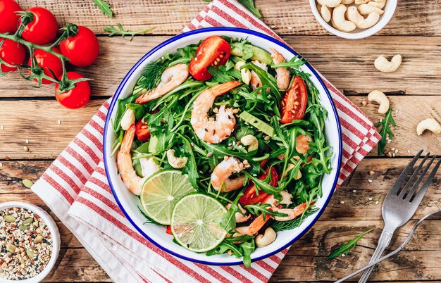 Homemade shrimp salad with tomato arugula avocado and cashew nuts Over wooden rustic background Top view