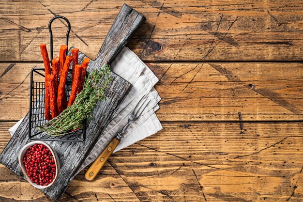 Homemade small thin kabanos sausages in a basket Wooden background Top view Copy space