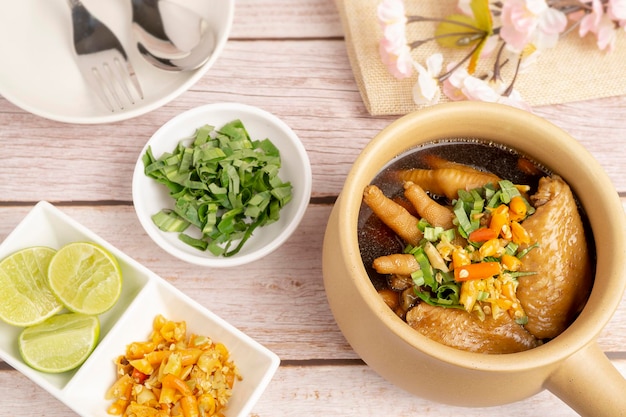 Homemade spicy chicken feet and wings served in clay pot on wooden table