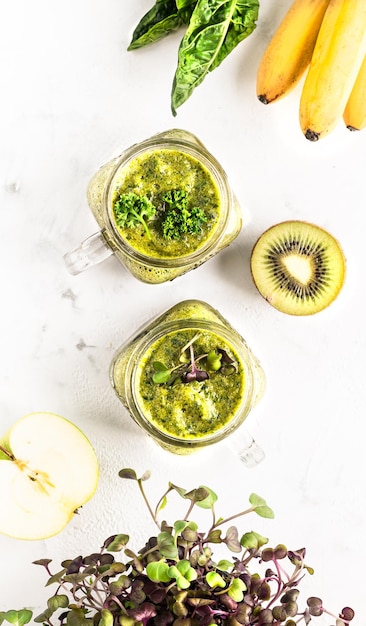 Homemade spinachbased green cocktail with banana apple and kiwi and wet greens in a jar top view