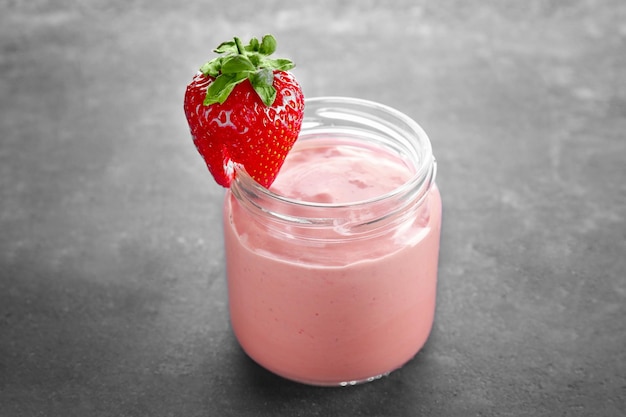 Homemade strawberry yogurt in glass jar on grey background