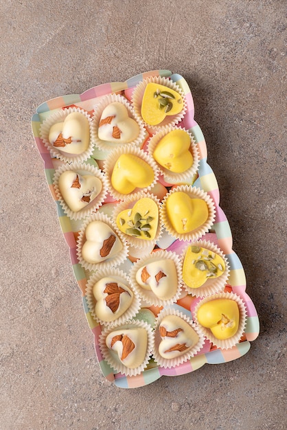 Homemade sweets made of white chocolate colored with turmeric extract, with almonds and pumpkin seeds