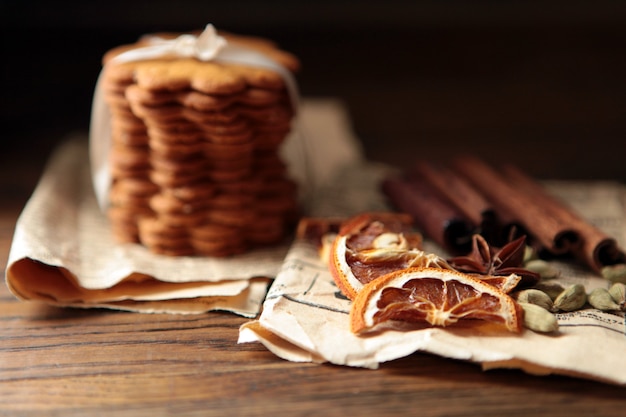 Homemade tasty gingerbread cookies on dark rustic wooden table, copy space. Healthy vegan organic nutrition concept. whole grain cookies with dried oranges, cinnamon, old paper, spices and herbs.