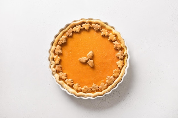 Homemade tasty pumpkin pie with autumn decorations and leaves for Thanksgiving Day on white