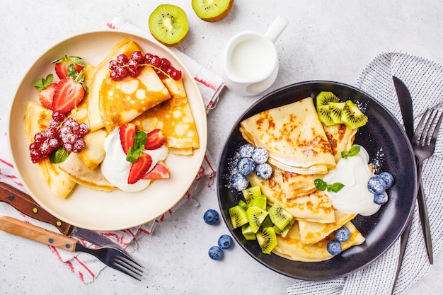 Homemade thin crepes served with curd cream, fruits 