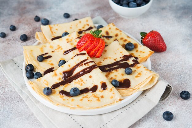 Homemade thin pancakes with berries and chocolate