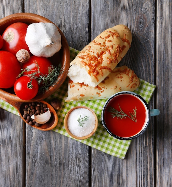 Homemade tomato juice in color mug bread sticks spices and fresh tomatoes on wooden background