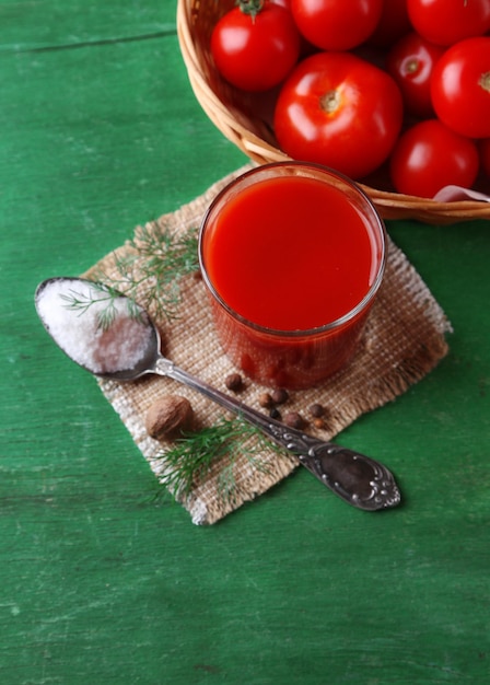 Homemade tomato juice in glass spices and fresh tomatoes on wooden background