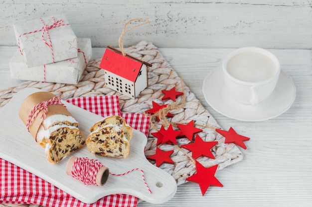 Homemade traditional christmas dessert stollen with dried berries, nuts and powdered sugar on top stands on white rustic wooden table