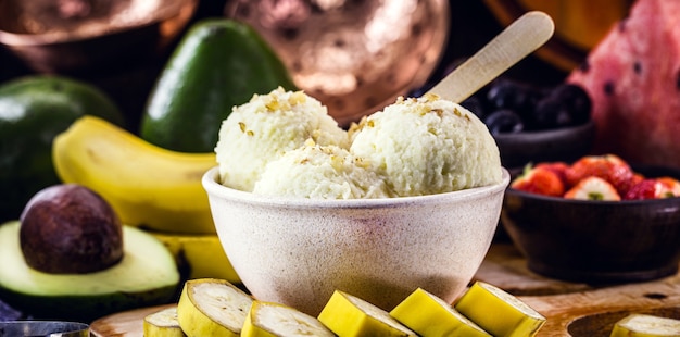 Homemade and vegan banana ice cream without milk in a recycled plastic bowl, with fruits in the surface